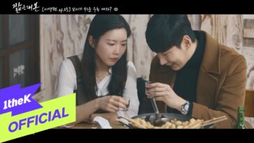 Um casal compartilha um momento íntimo, brindando com copos em uma mesa cheia de comida.