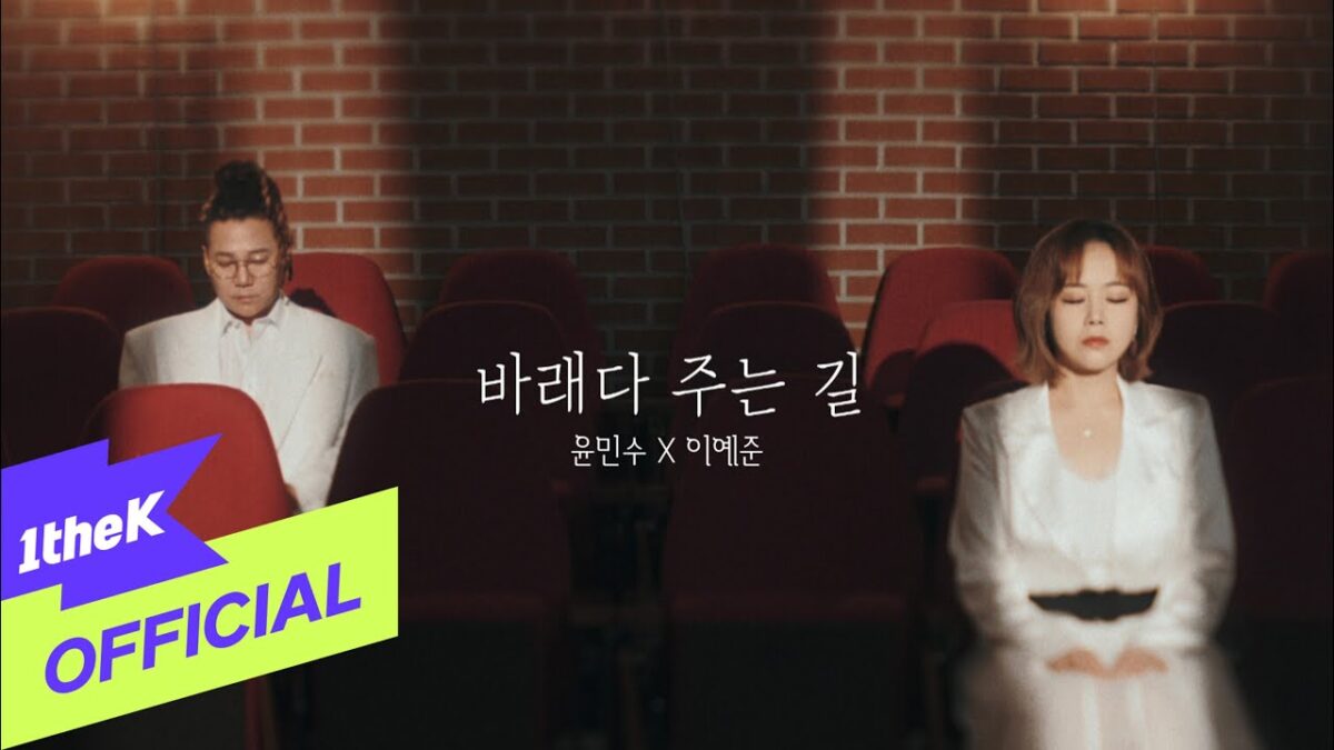Yun Min Soo e Lee Ye Joon sentados em cadeiras de teatro, com expressões concentradas e trajes brancos.