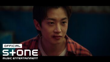Kim Min Seok com expressão intensa, usando camisa xadrez, durante apresentação da OST "Sirius" de Typhoon Family.