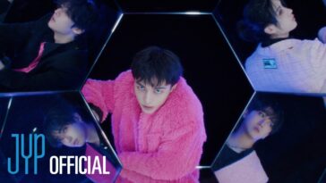 Membros do Stray Kids em um cenário futurista, com destaque para um deles usando um casaco rosa.