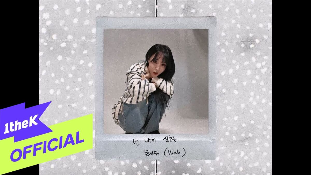 Moon Byul sentada em um fundo neutro, com expressão surpresa, usando uma blusa listrada e calças jeans.