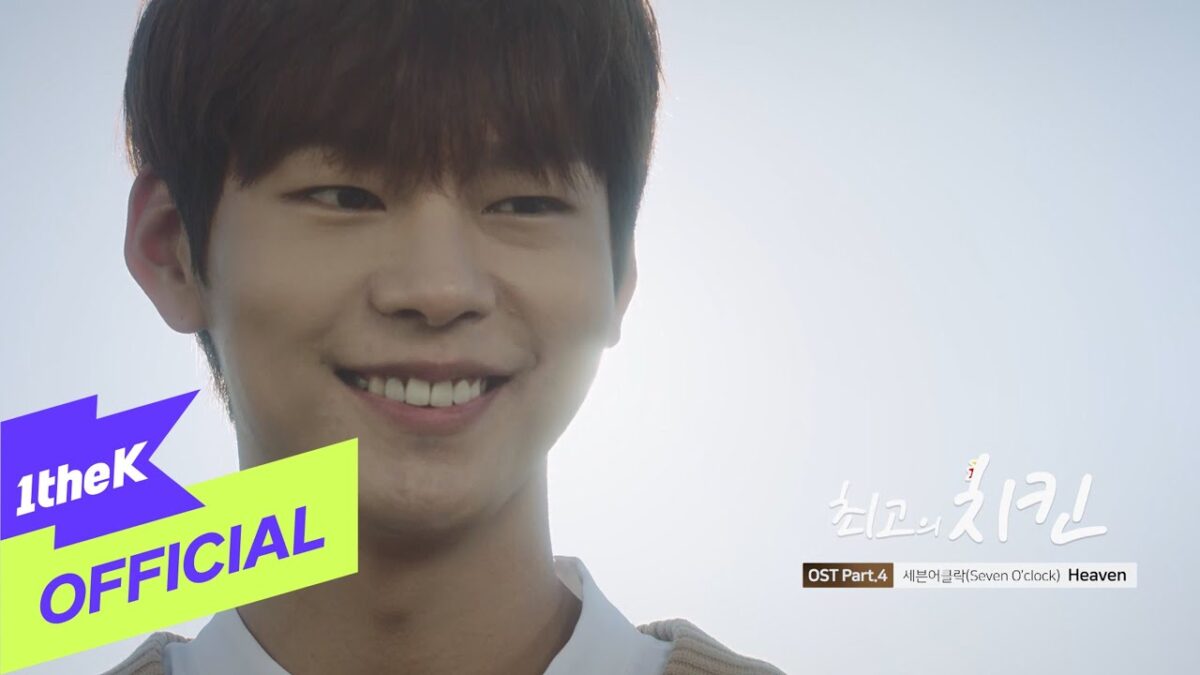 Jovem sorridente em um cenário claro, com luz suave ao fundo e logotipo do canal 1theK no canto inferior esquerdo.