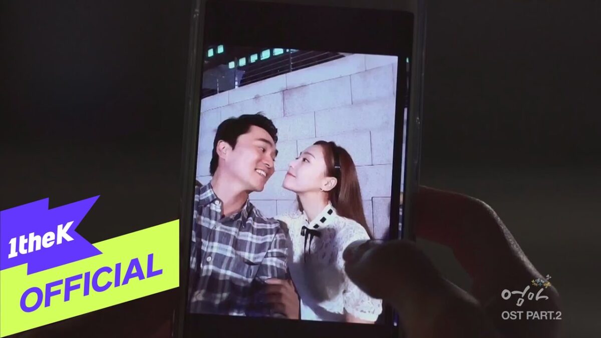 Casal sorrindo um para o outro, capturado em uma foto exibida em um celular.