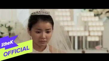 Noiva com expressão triste, usando véu e tiara, em ambiente de cerimônia de casamento decorado.