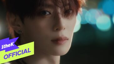 Close-up de um jovem com cabelo solto e olhar intenso, com fundo desfocado em luzes coloridas.