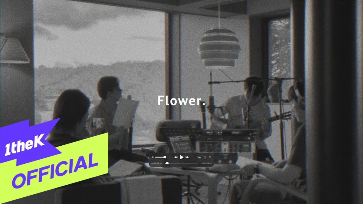 Quatro músicos em estúdio, tocando instrumentos e ensaiando a canção "Flower" em um ambiente iluminado.