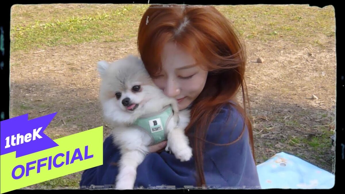 Mulher com cabelo ruivo abraçando um cachorro Pomerânia em um ambiente ao ar livre.