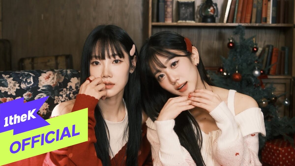 Kim Yuna e Oyeon posam juntas em ambiente natalino, com árvore decorada e livros ao fundo.