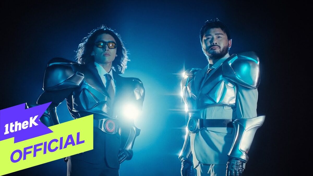Dois homens em trajes futuristas de armadura, iluminados por luzes dramáticas em fundo escuro.