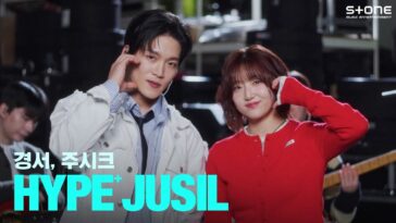Gyeongseo e Joosiq posam juntos, sorrindo, durante apresentação ao vivo, com músicos ao fundo.