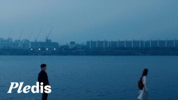 Dokyeom e Seungkwan em um cenário azul à beira do rio, com prédios ao fundo e atmosfera melancólica.