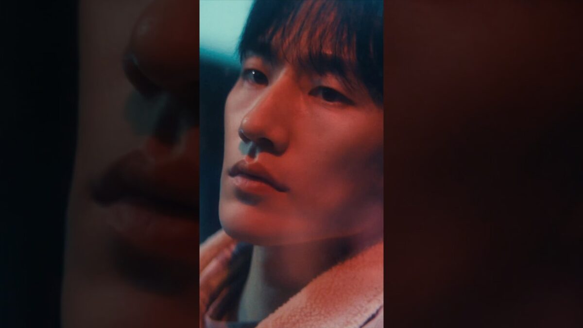 Dokyeom e Seungkwan em close-up, com luzes em tons de azul e vermelho, em uma atmosfera cinematográfica.