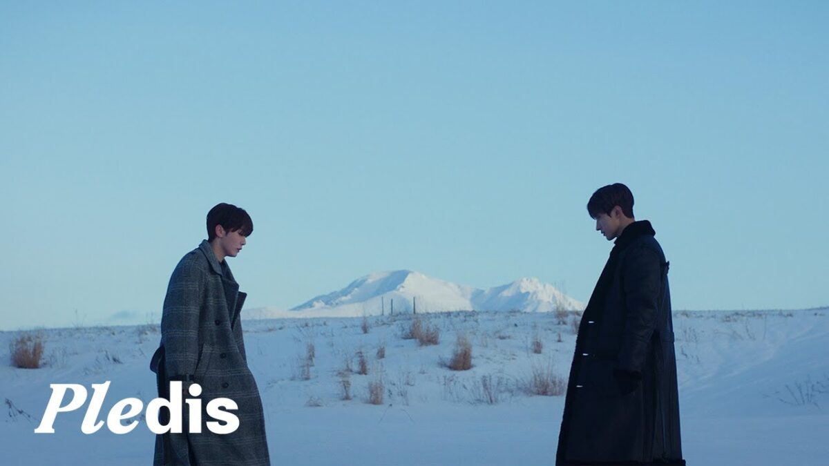 Dokyeom e Seungkwan em um campo nevado, com montanhas ao fundo, ambos com expressões pensativas.