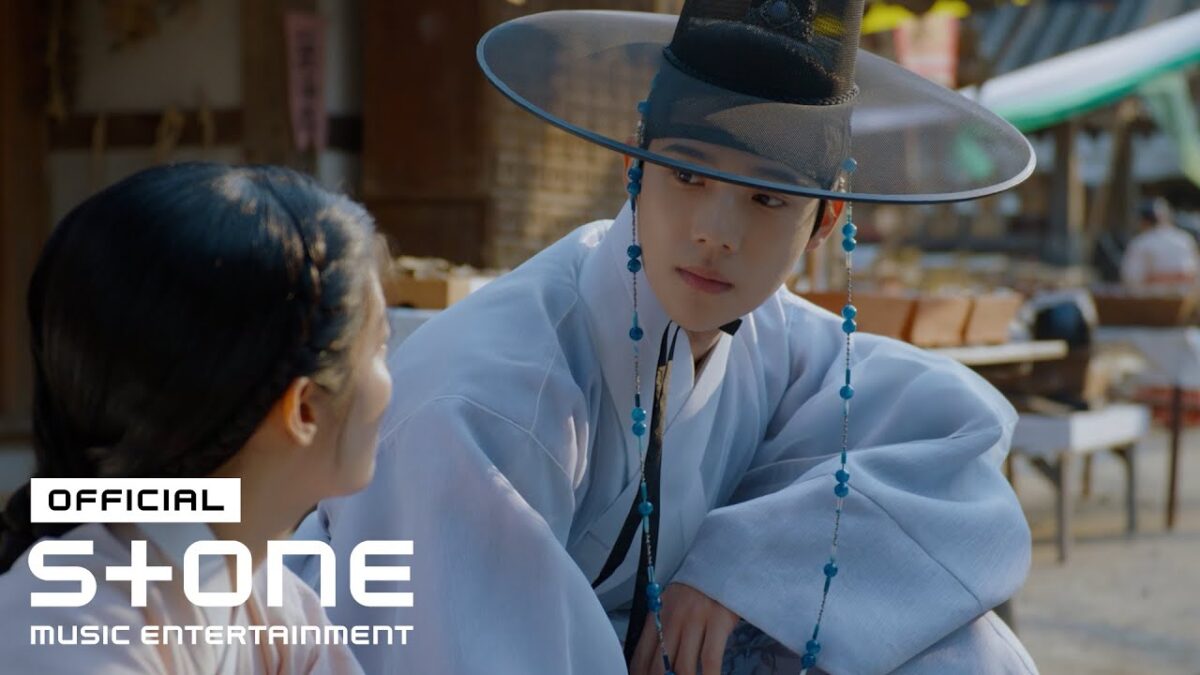 Ha Hyun Sang, vestido com traje tradicional, observa uma mulher em uma cena marcante ao ar livre.