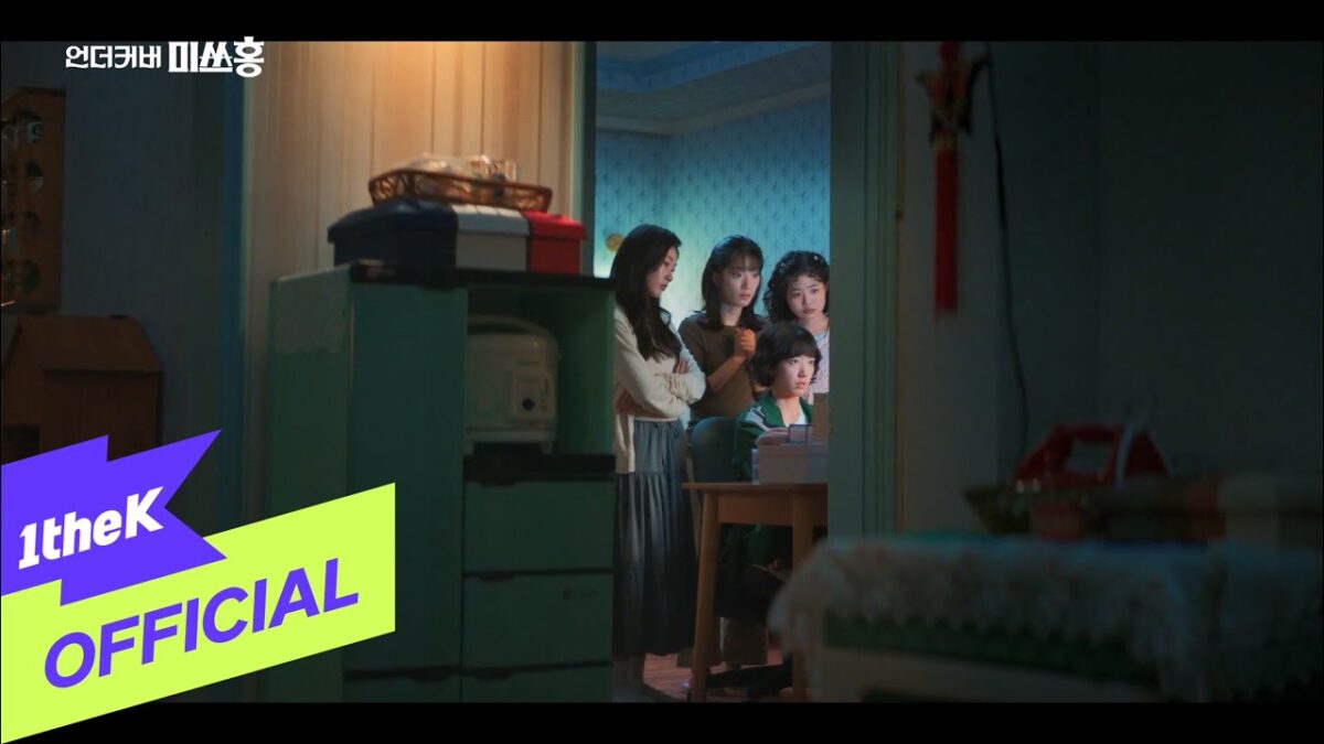 Quatro garotas observam atentamente uma tela de computador em um ambiente iluminado suavemente.