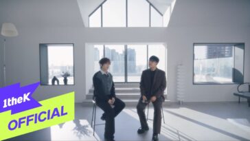 Song I Han e Jeon Sang Keun conversam em um ambiente moderno e iluminado, com vista para a cidade.