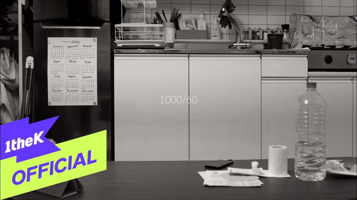 Cozinha minimalista com calendário na geladeira e objetos de uso diário sobre a mesa.