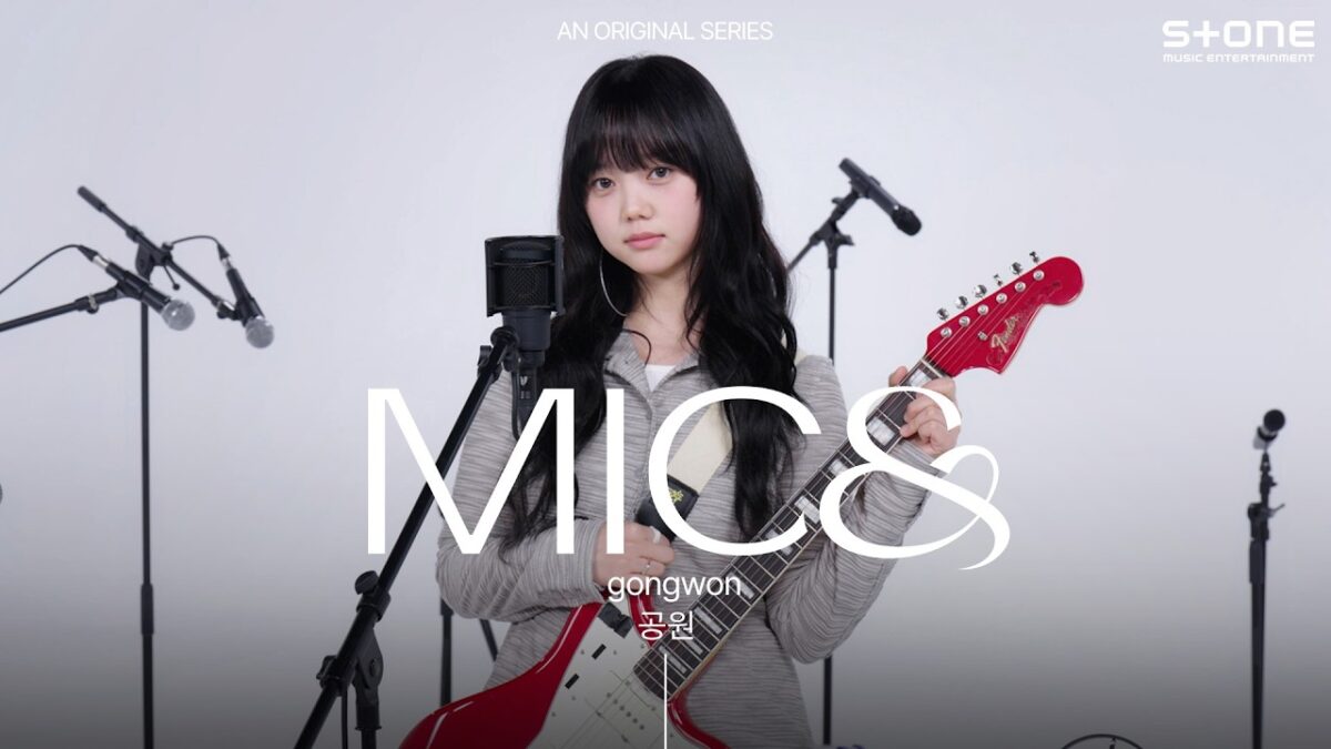 Gongwon toca guitarra e canta ao vivo, transmitindo emoção durante a apresentação de 'Minha Arma'.