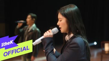 SULLYOON canta ao vivo com microfone, enquanto Parc Jae Jung se apresenta ao fundo em um palco iluminado.
