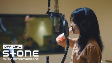 Kim Taeri gravando em estúdio, com fones e microfone, concentrada na performance.
