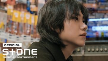 Jovem com cabelo curto e escuro, olhando pensativamente em um ambiente iluminado por luzes coloridas.