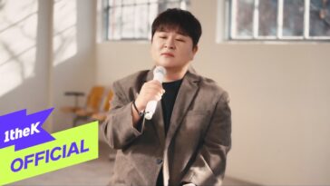 Huh Gak canta emocionado com microfone em ambiente iluminado, transmitindo intensidade na interpretação de "Crazy Love Song".