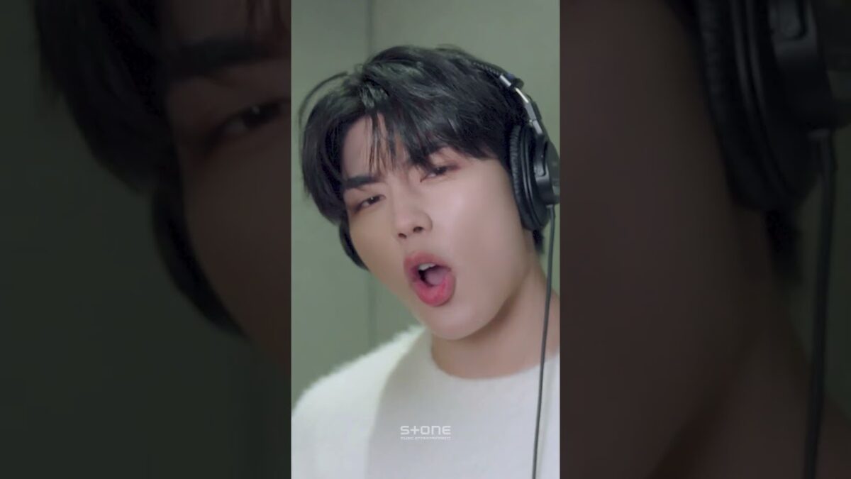 Seok Matthew canta animadamente em estúdio, usando fones de ouvido e com expressão intensa.