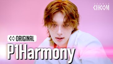 Artista de P1Harmony com cabelo ondulado, olhando intensamente para a câmera em fundo rosa.