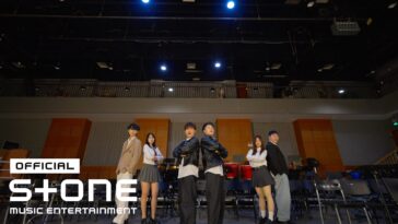 Grupo de jovens posando em um palco com luzes, em um cenário de apresentação musical.