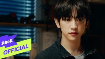 Soobin, com expressão reflexiva, está em um ambiente iluminado por luz natural, vestindo um suéter escuro.