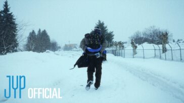 Homem caminha em uma estrada coberta de neve, carregando uma criança nas costas sob um céu nublado.