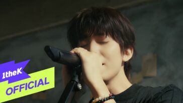 Cantor do SF9 interpretando "Love Comes Slowly" ao vivo, com microfone e expressão intensa, em ambiente descontraído.