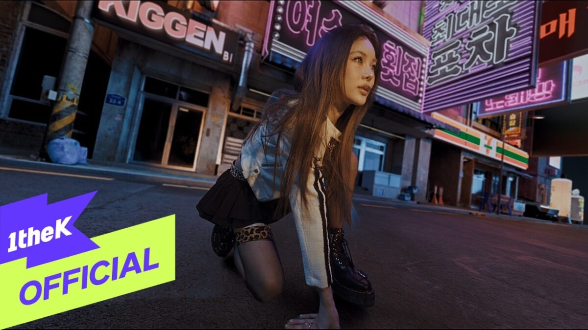 Jovem mulher agachada em uma rua iluminada por neon, vestindo saia e botas, com letreiros em coreano ao fundo.