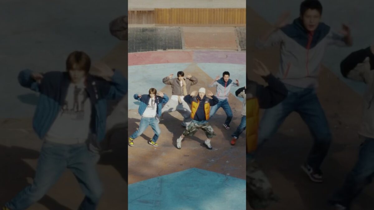 Grupo de dançarinos se apresentando em uma coreografia em um espaço ao ar livre com piso colorido.