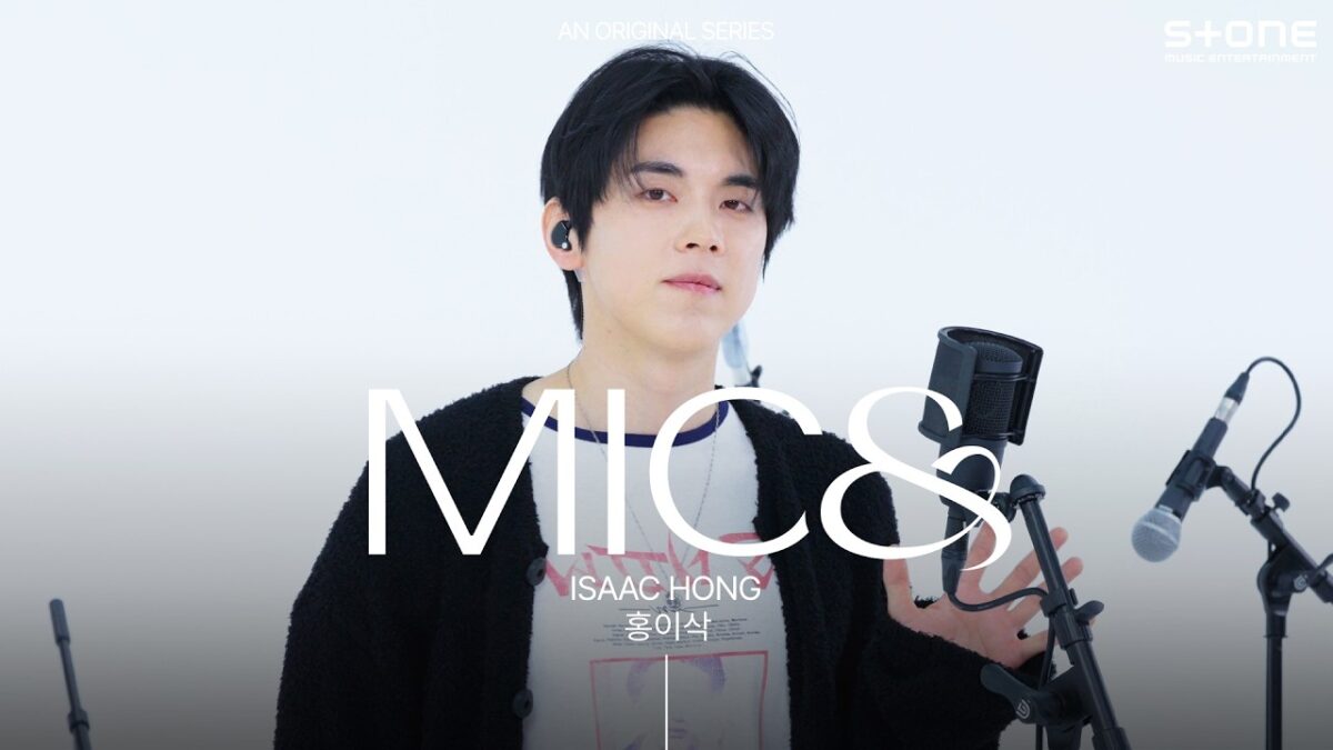 Hong Isak se apresenta ao vivo, com microfones e expressão concentrada, em performance da música "Doesn't Matter".