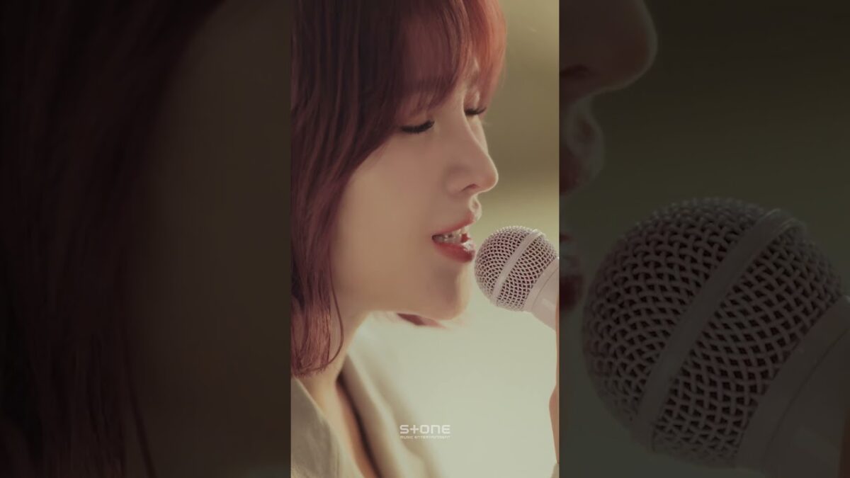 GUMMY canta com emoção em um microfone durante a apresentação ao vivo de "Bomcheoreom Neon".