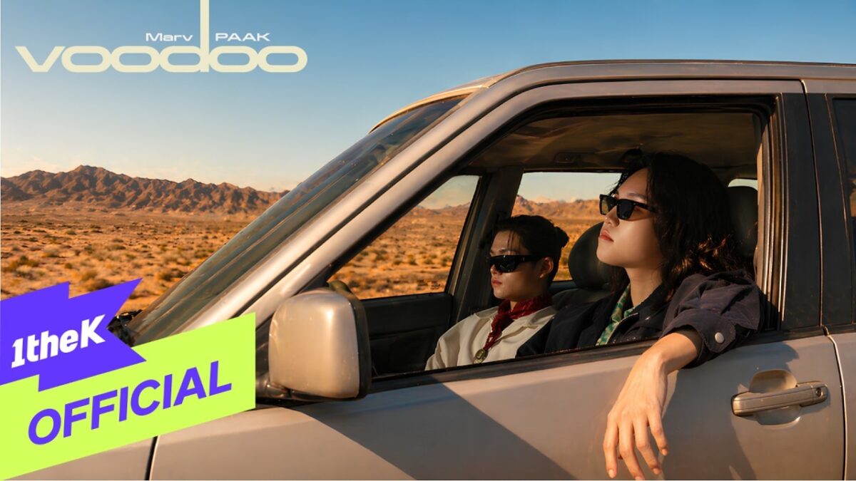 Marv e PAAK relaxam em um carro com paisagem desértica ao fundo, ambos usando óculos escuros.