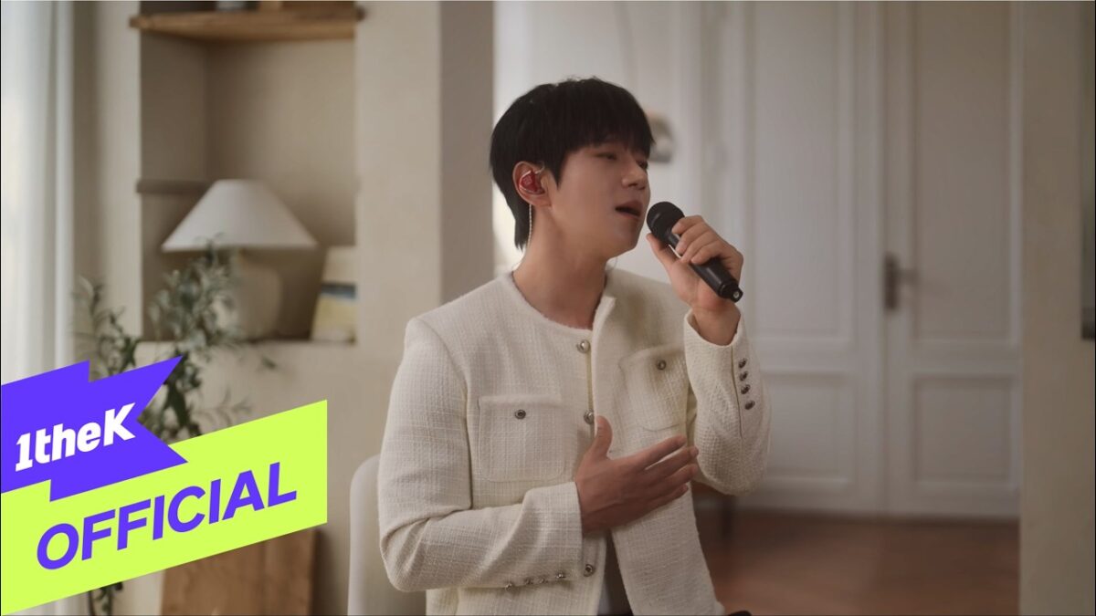 Hwang Chi Yeul canta com emoção em um ambiente claro e moderno, segurando um microfone.