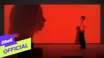 Um homem em pé observa uma projeção de perfil feminino em um fundo vermelho.