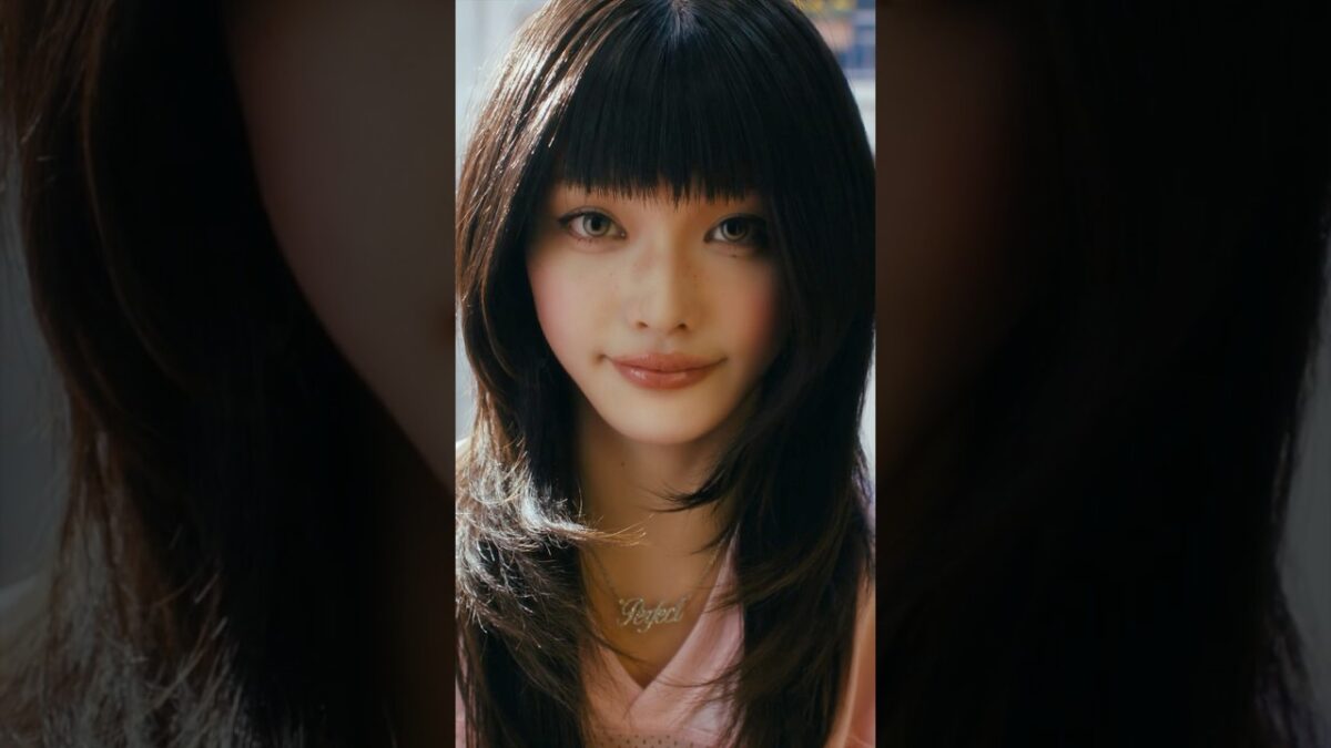 Uma jovem com cabelo longo e liso, usando um colar com a palavra "Perfect".