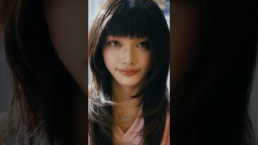 Uma jovem com cabelo longo e liso, usando um colar com a palavra "Perfect".