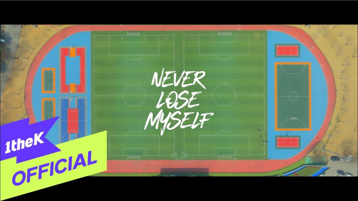 Campo esportivo visto de cima com a frase "NEVER LOSE MYSELF" em destaque no centro.