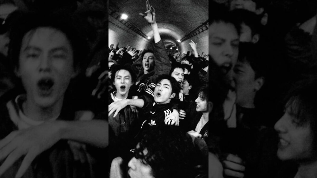 Grupo de jovens animados em um túnel, expressando entusiasmo e energia durante a performance "TNT".