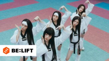 Seis dançarinas em trajes de artes marciais performam uma coreografia em um cenário colorido.