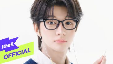 Jovem com cabelo escuro e óculos, ouvindo música com fones de ouvido e segurando um plugue de áudio.