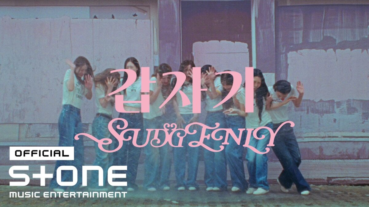Grupo de garotas em camisetas brancas e jeans, dançando em frente a uma parede colorida com a palavra "Suddenly".