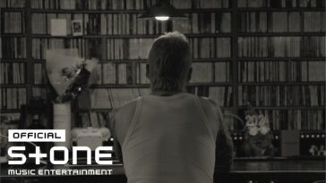 Homem de costas, com cabelo curto e tatuagens, observa prateleira cheia de discos em ambiente iluminado.