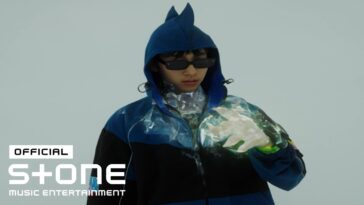 Jovem com óculos escuros e jaqueta azul, manipulando efeitos visuais brilhantes com as mãos.