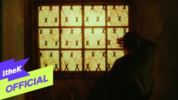 Homem observa pela janela em um ambiente com luz amarelada e detalhes de uma grade decorativa.
