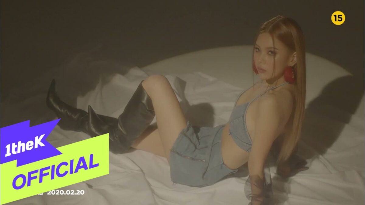 Moon Sujin posa com um olhar sedutor, vestindo um conjunto de jeans e botas altas em um cenário minimalista.